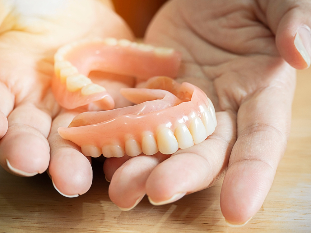 Close,up,of,female,hands,holding,flexible,nylon,denture.,dental