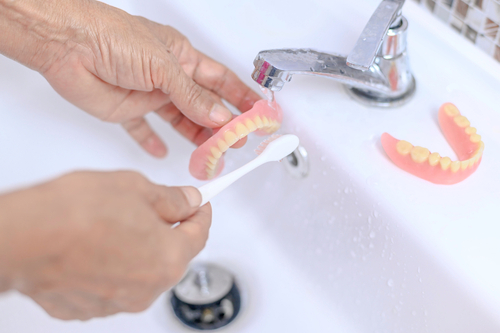 Brush,old,woman,hand,to,clean,denture