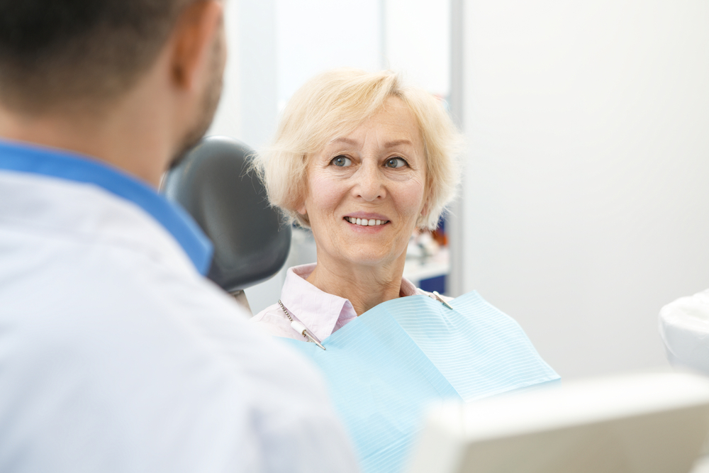 Senior,woman,smiling,listening,to,her,dentist,during,consultation,copyspace